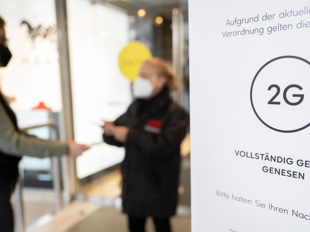 In Niedersachsen und Bayern wurde die 2G-Regel gerichtlich gekippt. Das Symbolfoto aus Stuttgart zeigt eine Mitarbeiterin eines Kaufhauses, die am 12. Januar 2022 am Eingang mit einem Smartphone den Impfnachweis einer Kundin kontrolliert.