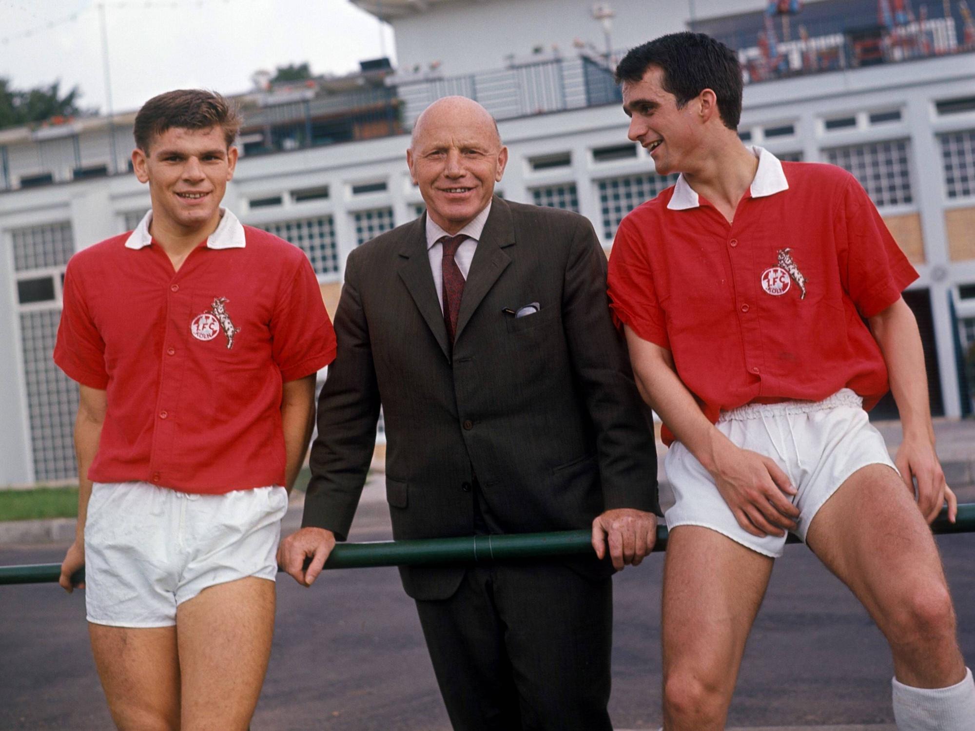 Trainer Georg Knöpfle steht zwischen Wolfgang Weber und Wolfgang Overath, die auf einer Stange sitzen.