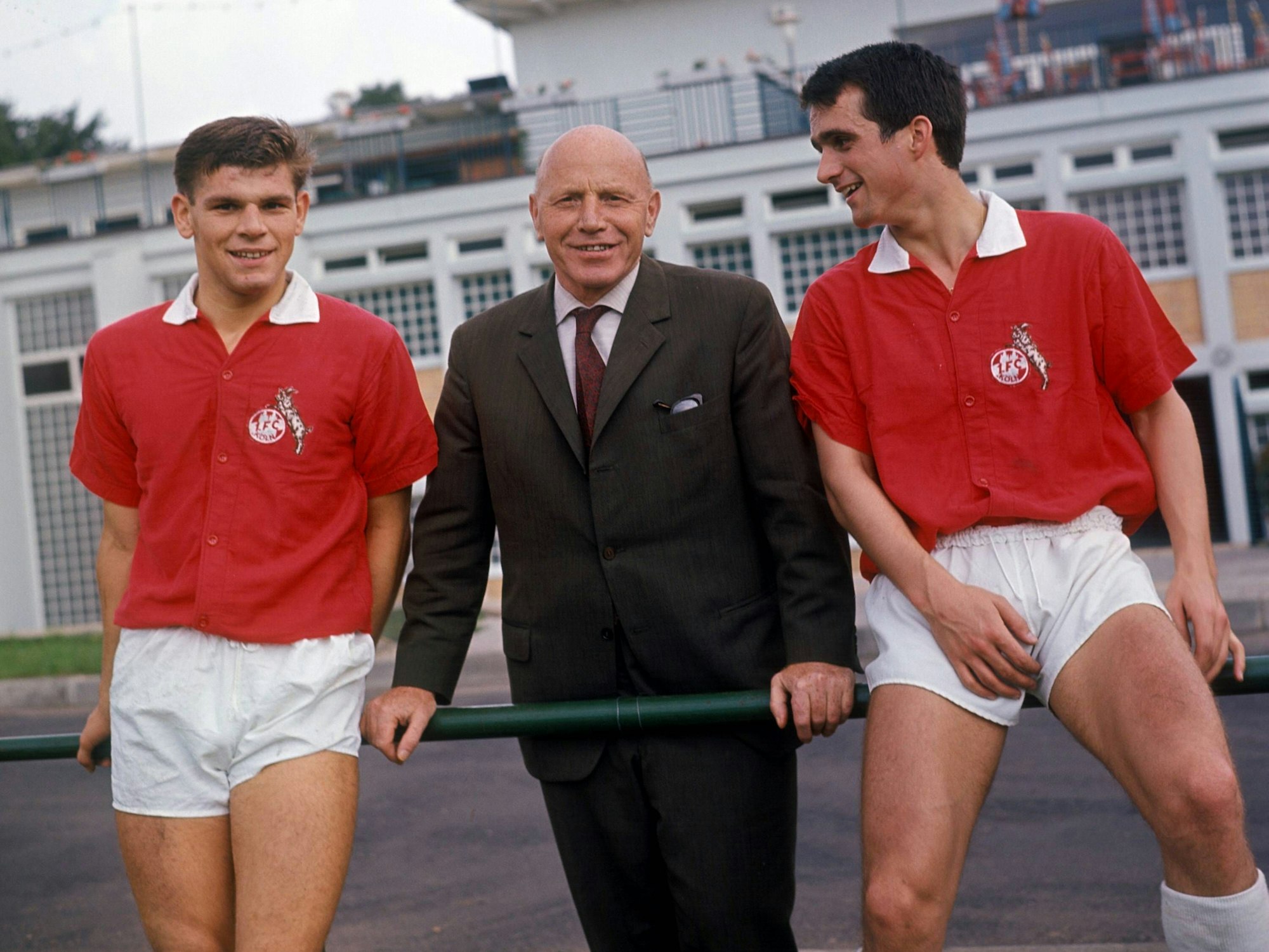 Trainer Georg Knöpfle steht zwischen Wolfgang Weber und Wolfgang Overath, die auf einer Stange sitzen.