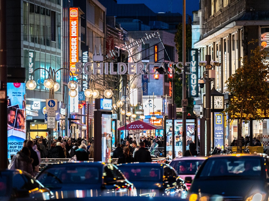 Die Kölner Schildergasse mit heller Beleuchtung im Abendlicht.