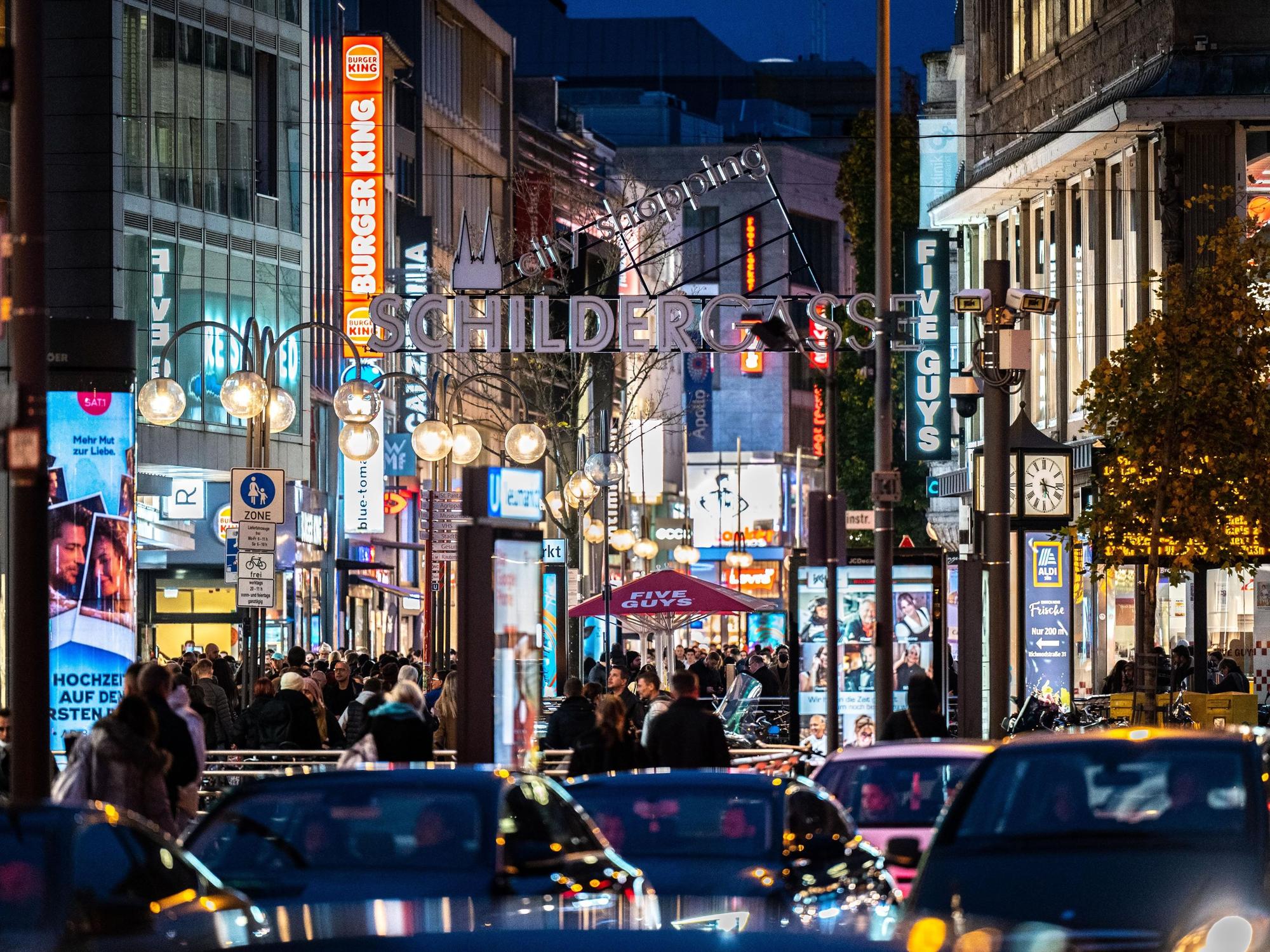 Die Kölner Schildergasse mit heller Beleuchtung im Abendlicht.
