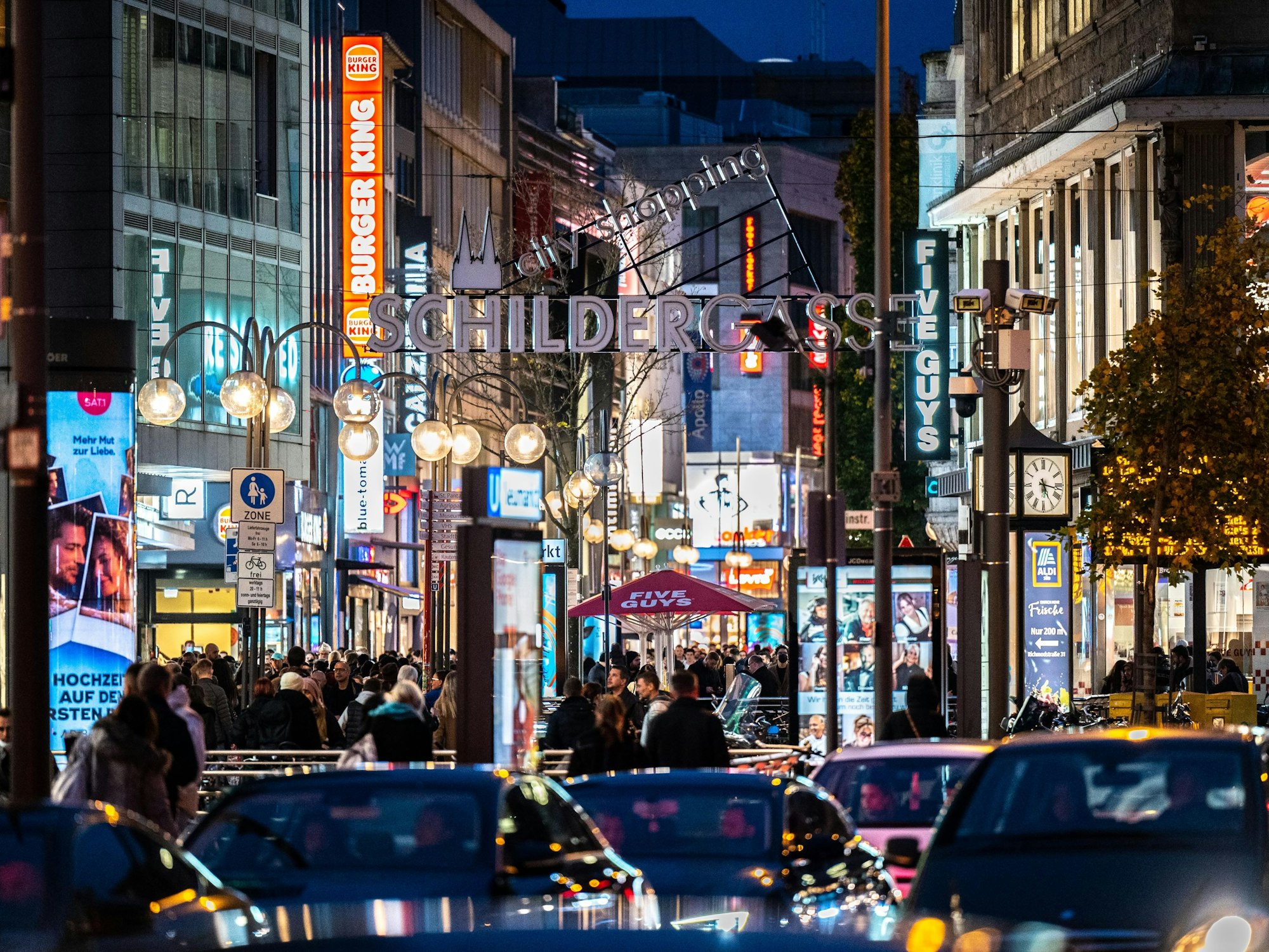 Die Kölner Schildergasse mit heller Beleuchtung im Abendlicht.