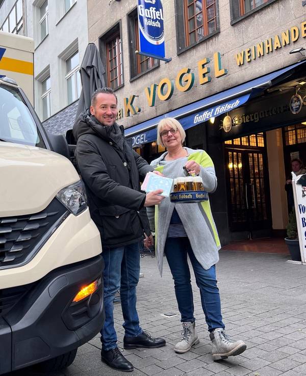 Bierlieferant Daniel Siebert (l.) übergibt am Eigelstein der Inhaberin des Weinhaus Vogel, Angelika, CDs.