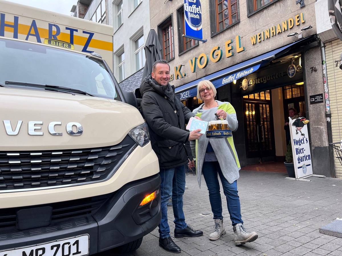 Bierlieferant Daniel Siebert (l.) übergibt am Eigelstein der Inhaberin des Weinhaus Vogel, Angelika, CDs.