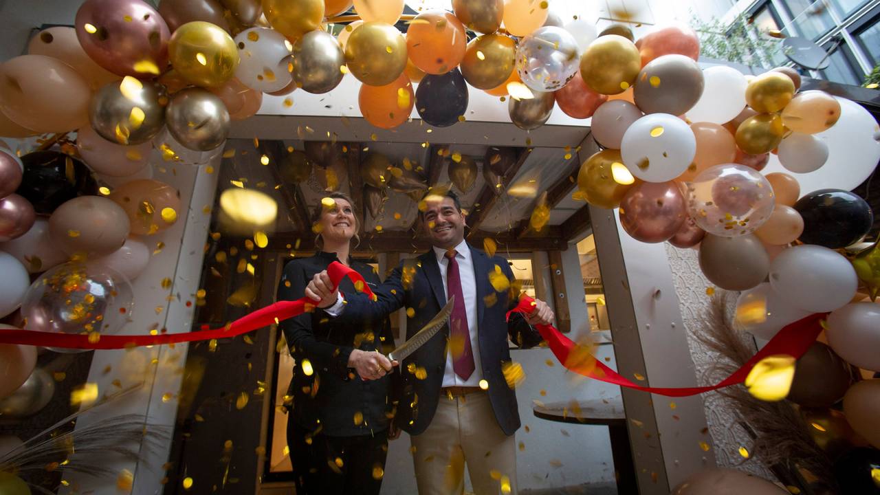 Julia Komp und Yunus Özananar durchschneiden ein rotes Band, drumherum sind viele Luftballons