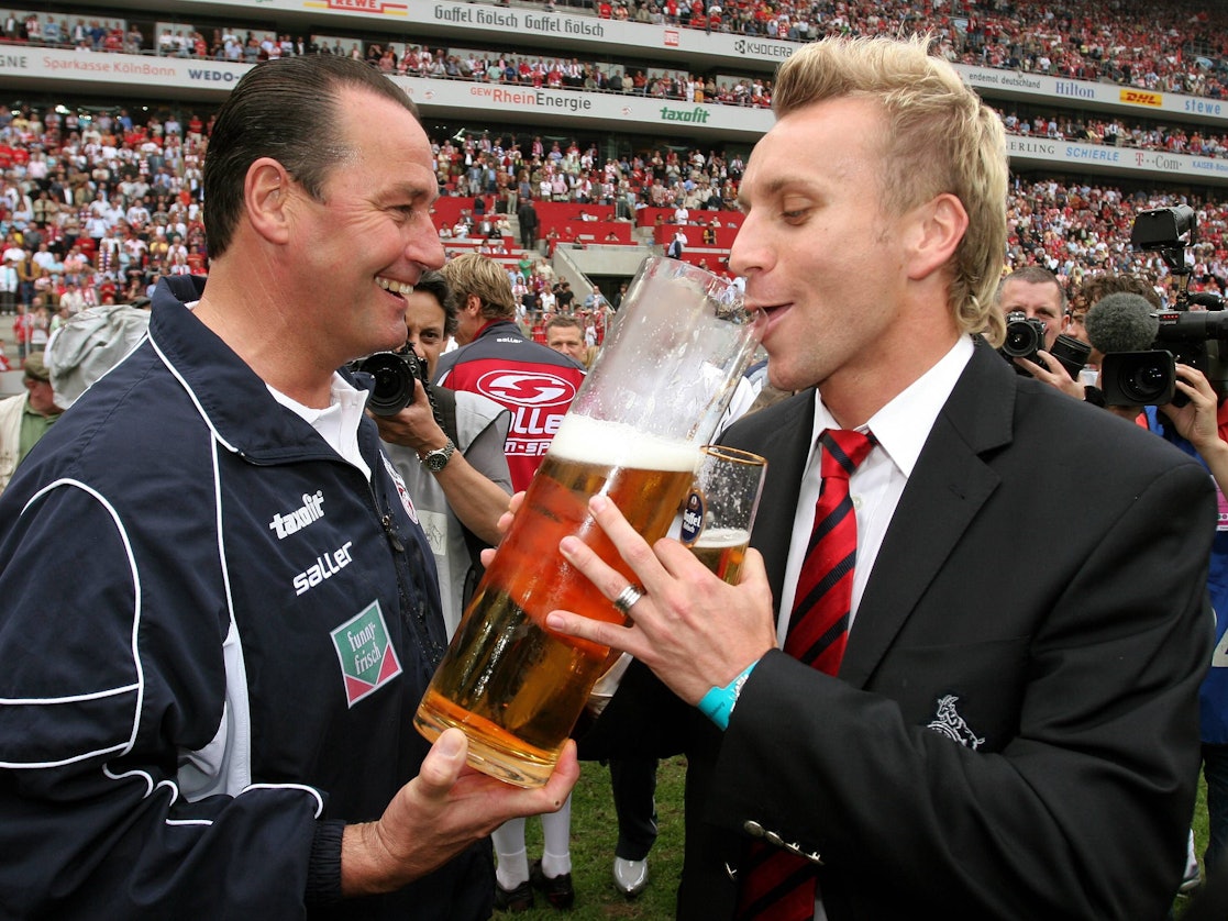 Trainer Huub Stevens (li.) verleitet Sebastian Schindzielorz (beide Köln) während der Aufstiegsfeier zum Bier trinken.