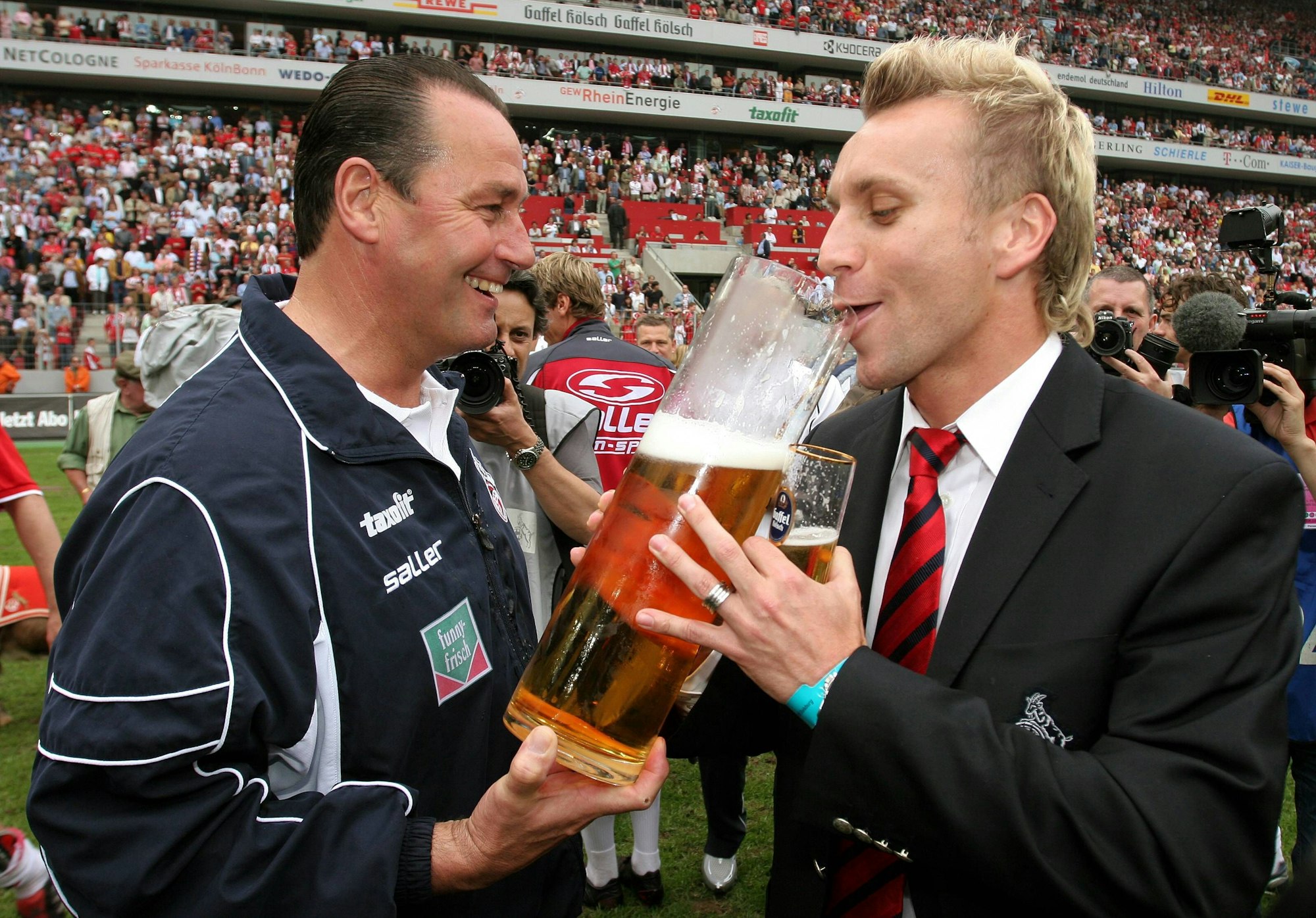 Trainer Huub Stevens (li.) verleitet Sebastian Schindzielorz (beide Köln) während der Aufstiegsfeier zum Bier trinken.