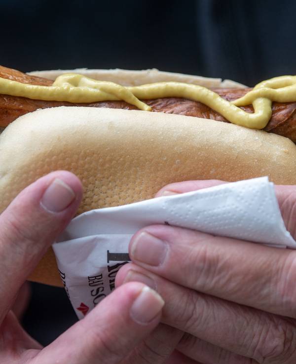 Ein Mann hält eine Bratwurst in der Hand.