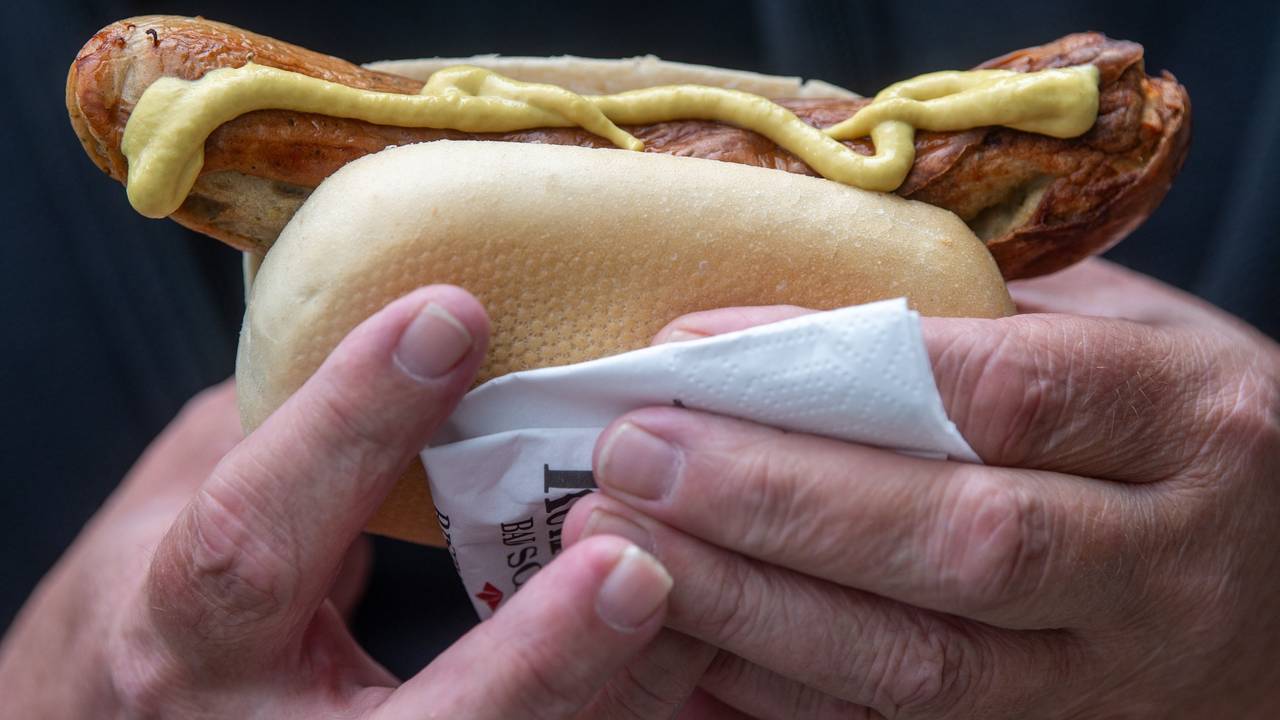 Ein Mann hält eine Bratwurst in der Hand.