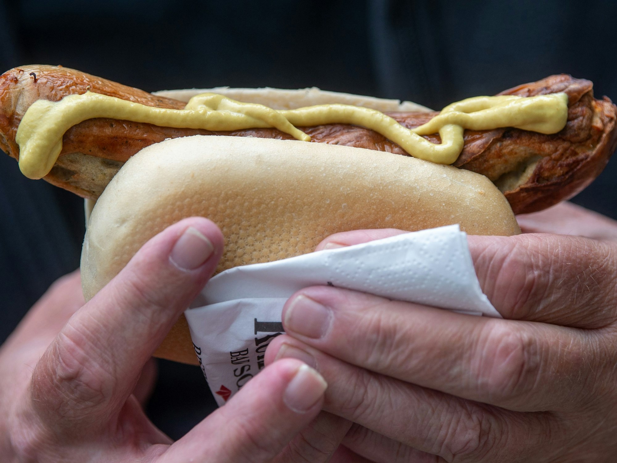 Ein Mann hält eine Bratwurst in der Hand.