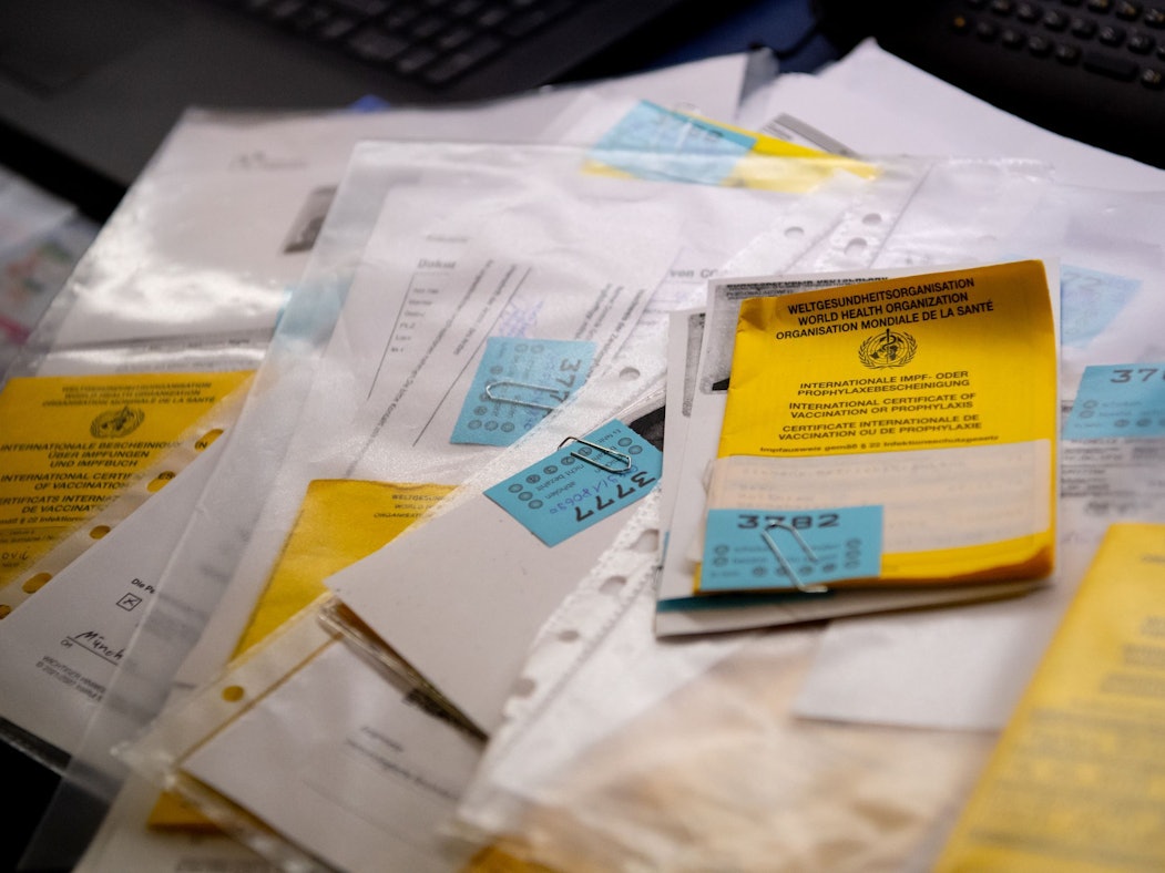 Zahlreiche Impfpässe liegen in einer Apotheke in einem Büro auf einem Tisch.