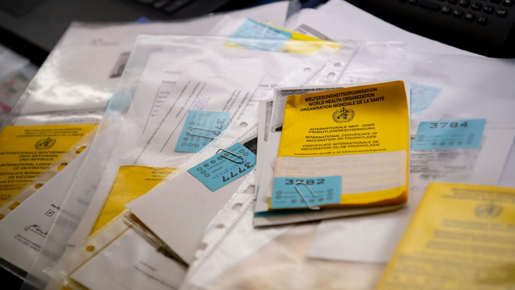 Zahlreiche Impfpässe liegen in einer Apotheke in einem Büro auf einem Tisch.