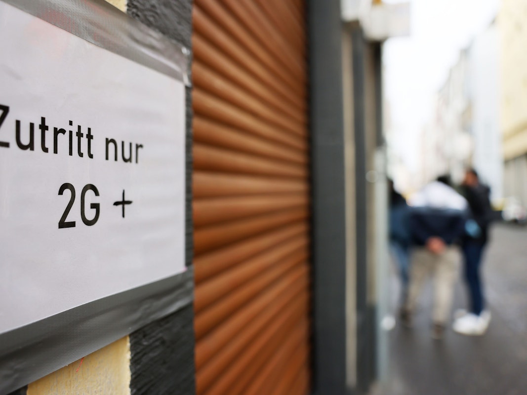 Ein Schild am Eingang einer Gaststätte mit geschlossenen Rollläden weist am 21. Januar 2022 auf die 2G-plus-Regel in Köln hin. Die Pandemie bestimmt weiterhin den Alltag.