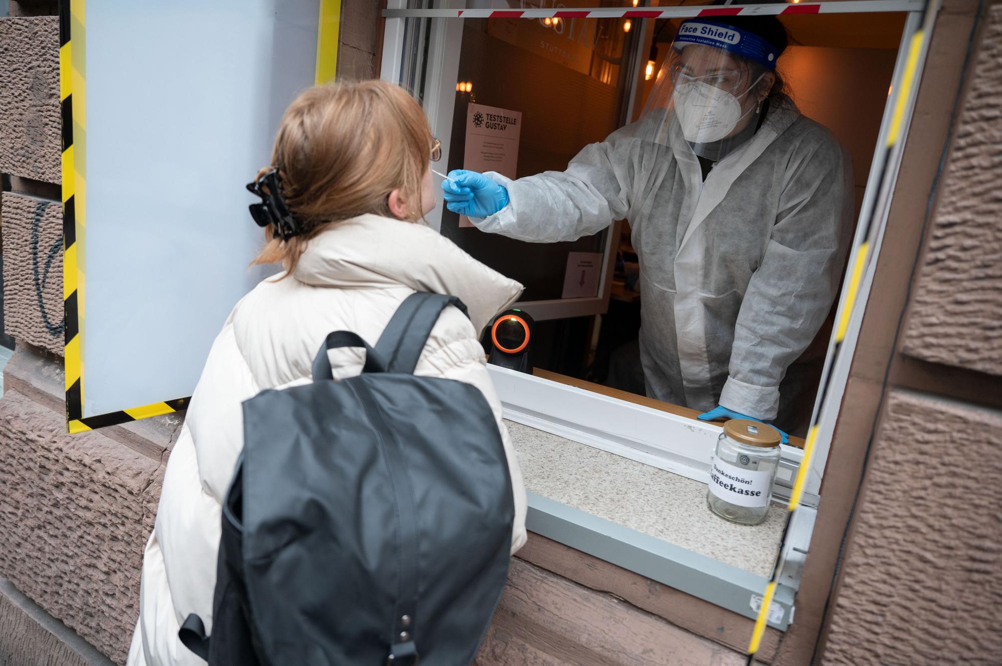 Eine Mitarbeiterin führt an einer Teststation, die sich in einem Café befindet und in der sich Passanten durch ein Fenster testen lassen können, einen Corona-Schnelltest durch.