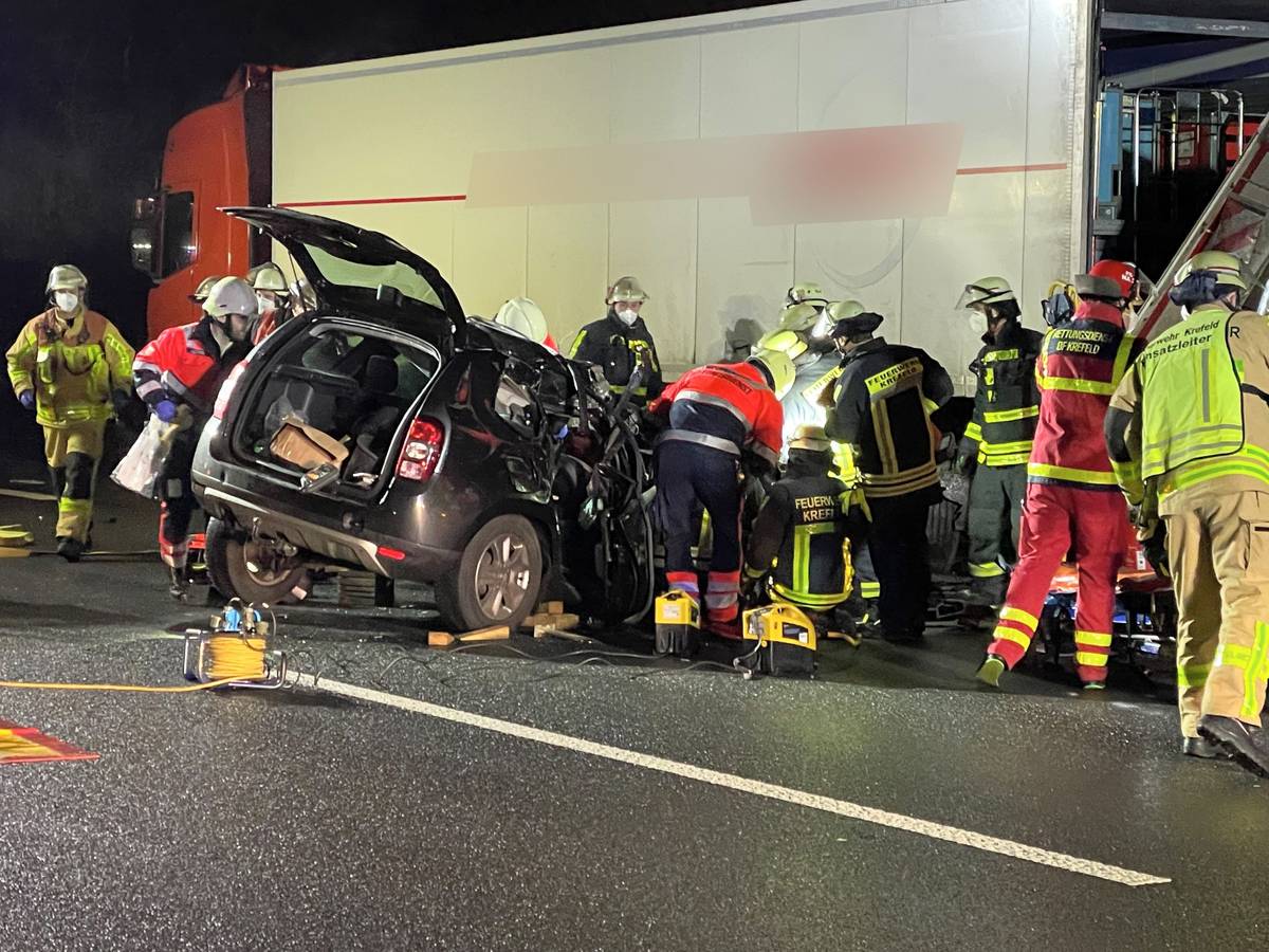 Rettungskräfte arbeiten auf der A57 an einem Pkw, der unter einen Lkw-Auflieger geraten ist.