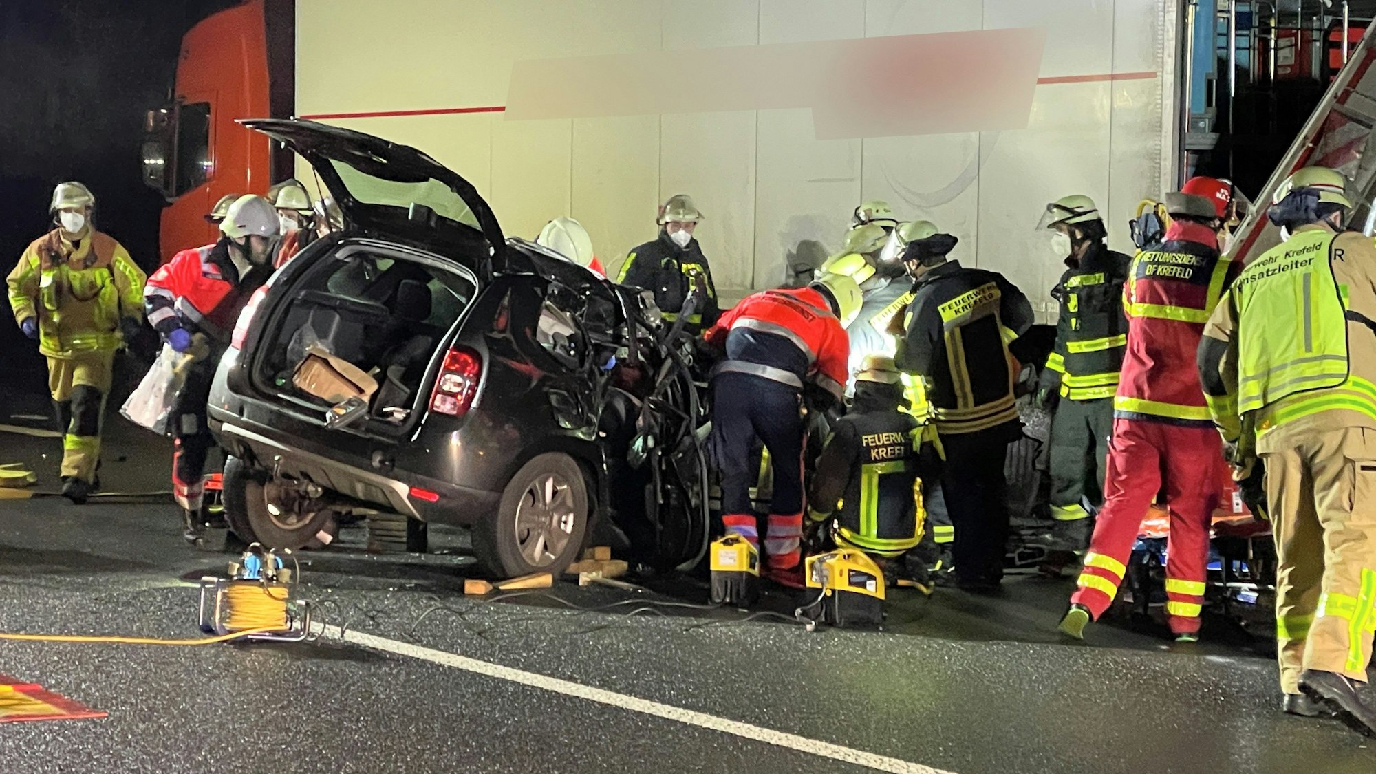 Rettungskräfte arbeiten auf der A57 an einem Pkw, der unter einen Lkw-Auflieger geraten ist.