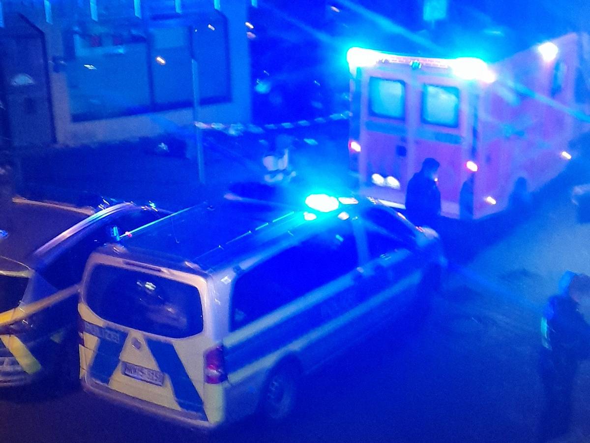 Rettungswagen und Polizeiautos mit Blaulicht stehen in einer Straße