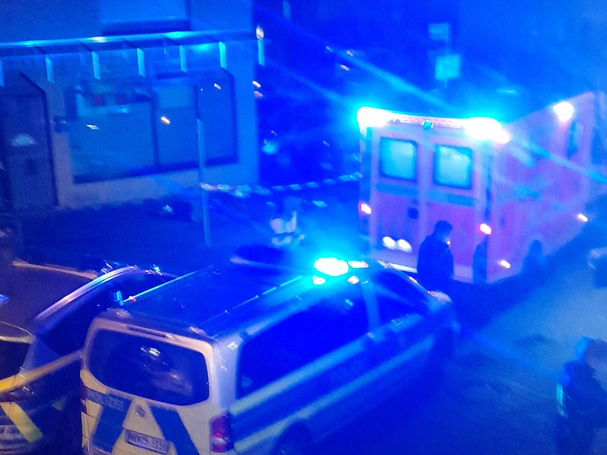 Rettungswagen und Polizeiautos mit Blaulicht stehen in einer Straße