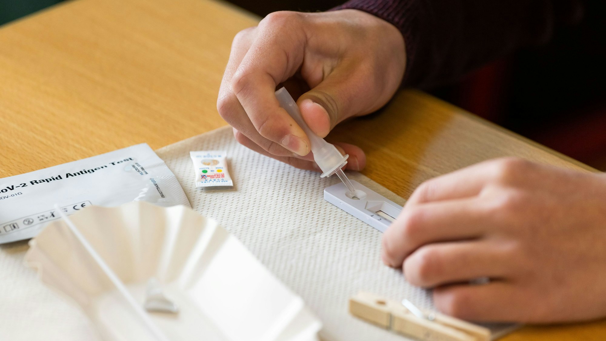 Ein Schüler träufelt fertige Lösungsflüssigkeit für den Corona-Selbsttest auf einen Teststreifen.