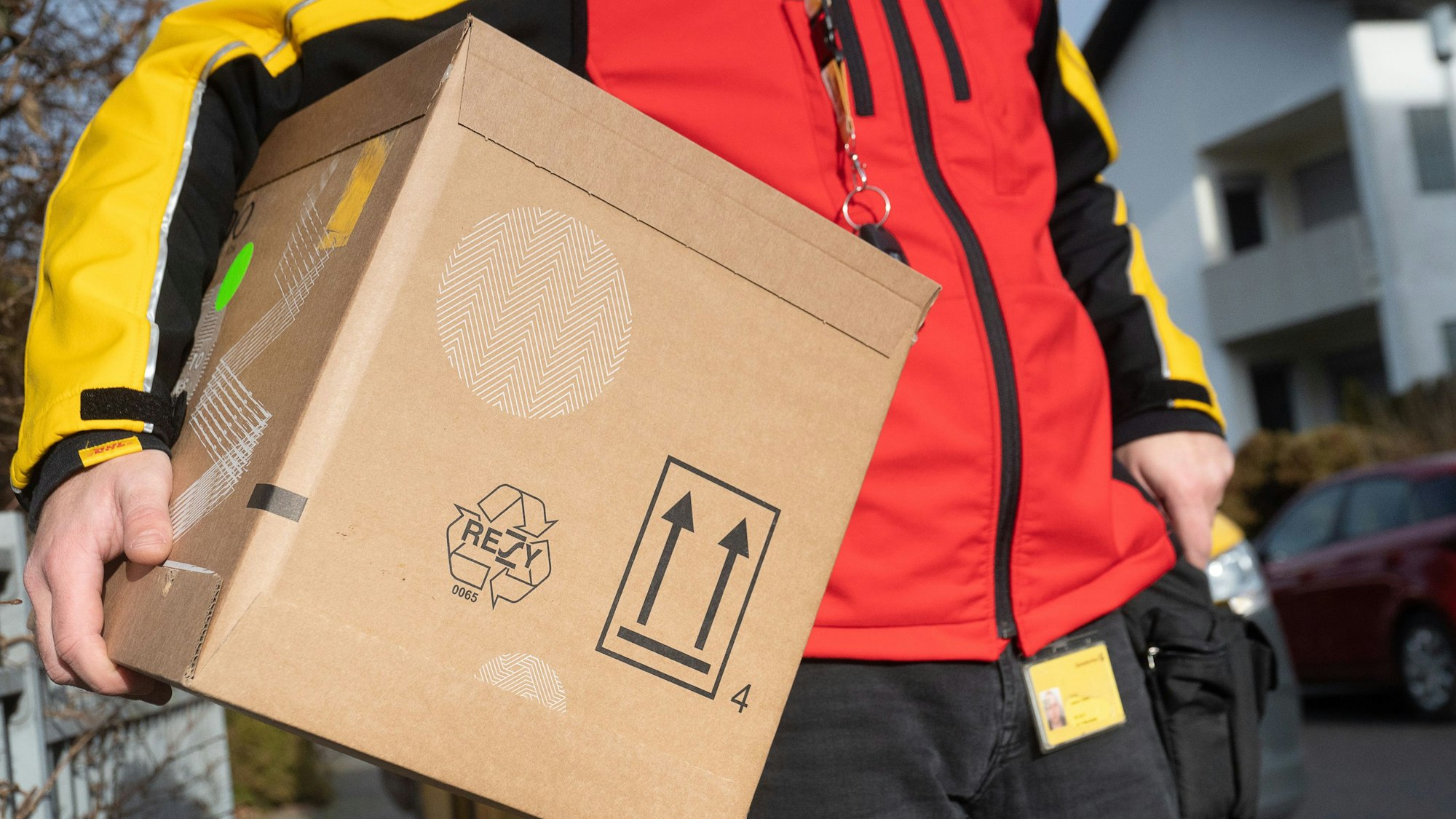 Ein DHL-Mitarbeiter trägt ein Paket unter seinem Arm. Foto vom 15. Dezember 2021.