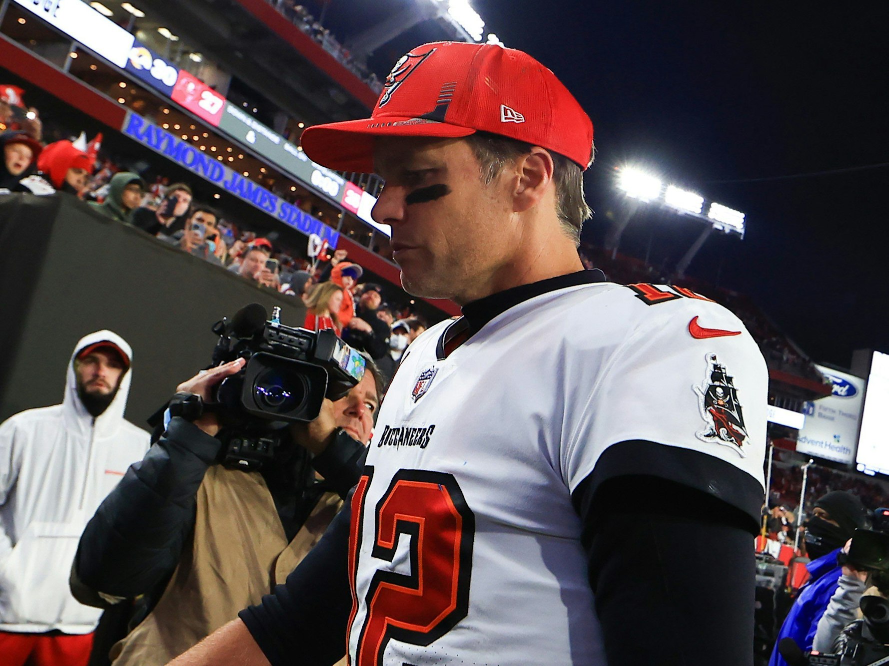 Tom Brady geht vom Feld, trägt eine rote Kappe.