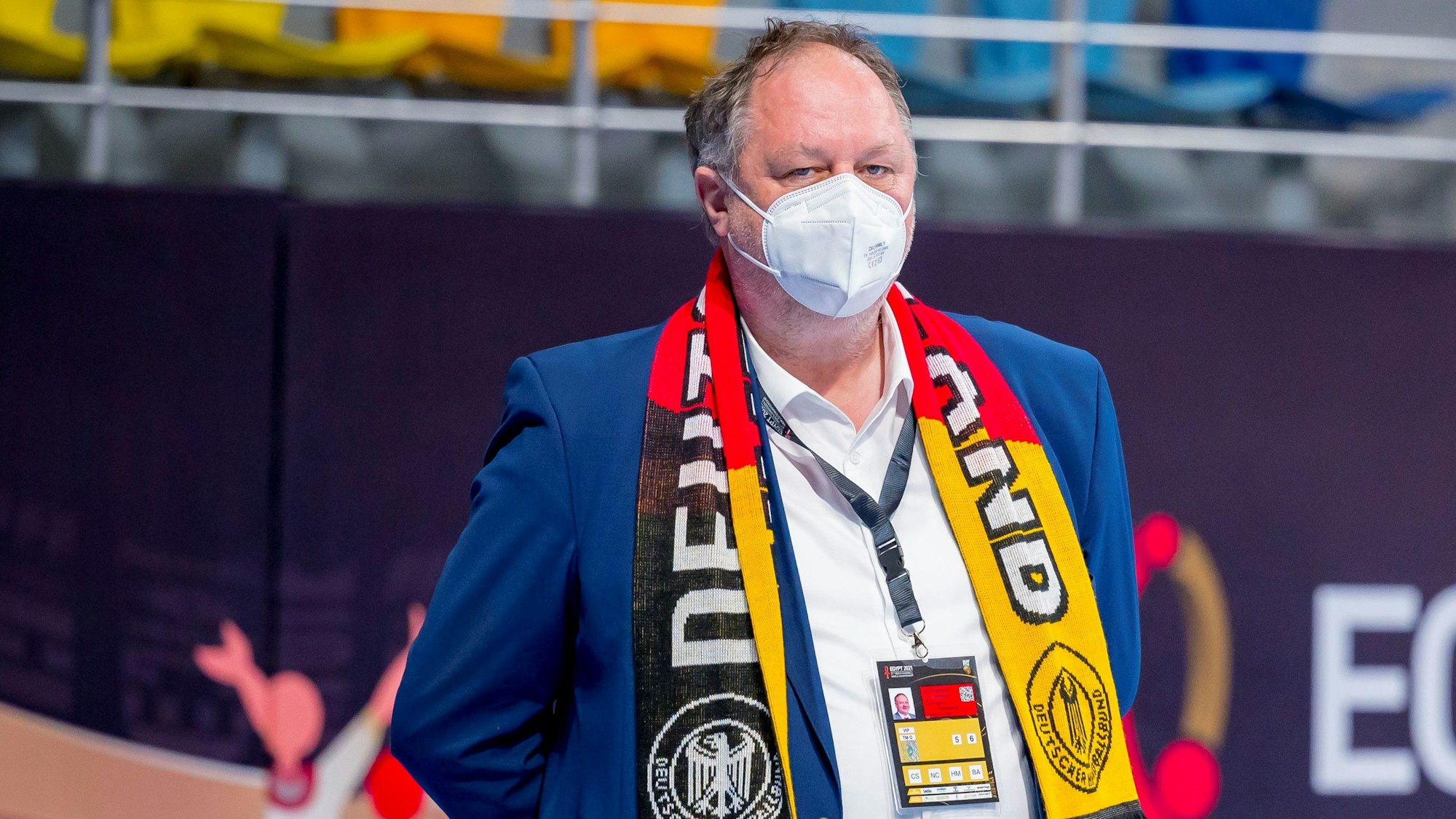 Andreas Michelmann steht bei einem Handball-Spiel mit Maske am Spielfeldrand.
