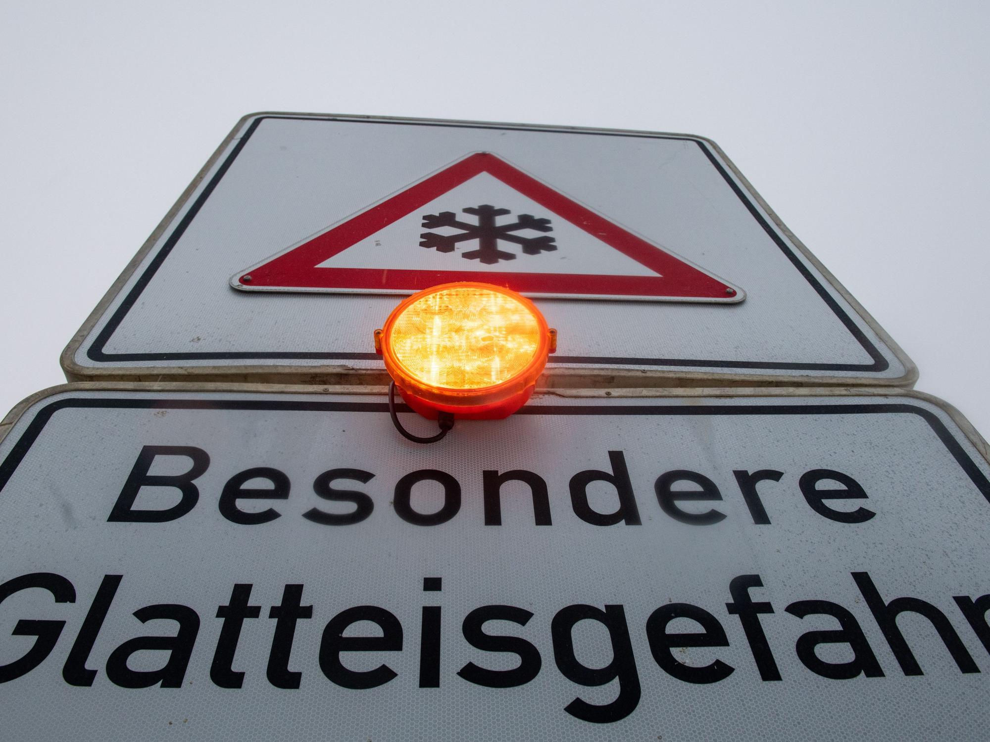 Ein Straßenschild warnt mit einer Blinkleuchte vor Glatteis.