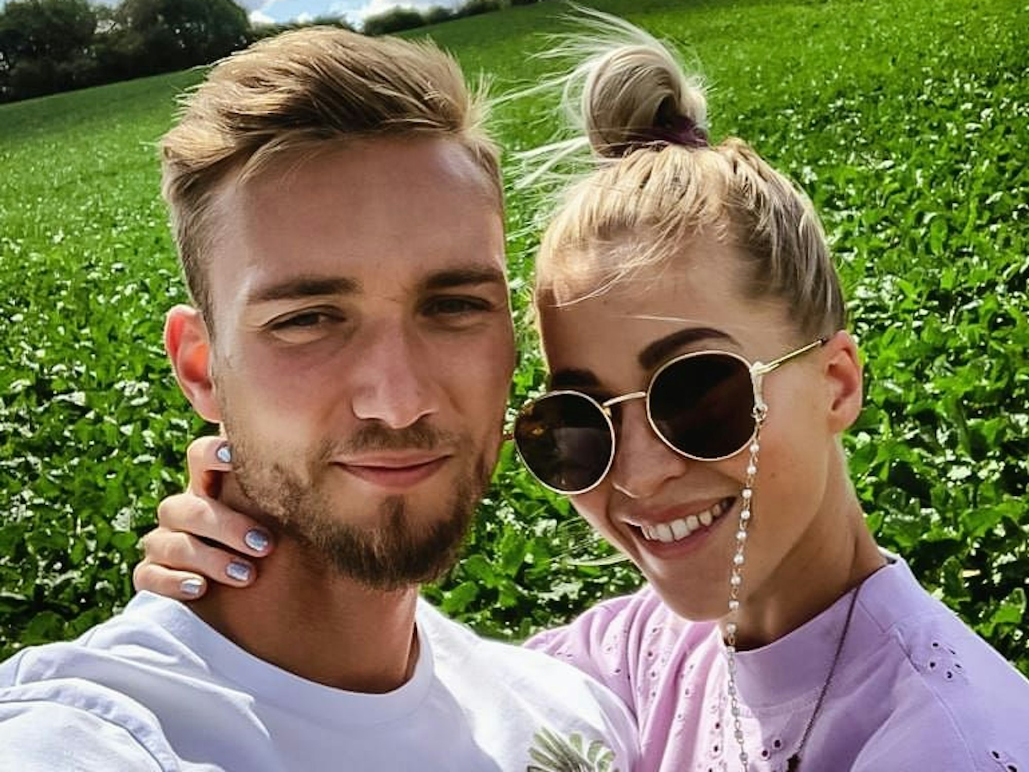 Tim Boss und Freundin Ilka machen zusammen ein Selfie. Ilka trägt eine Sonnenbrille und fasst Tim Boss mit der rechten liebevoll Hand an den Nacken.