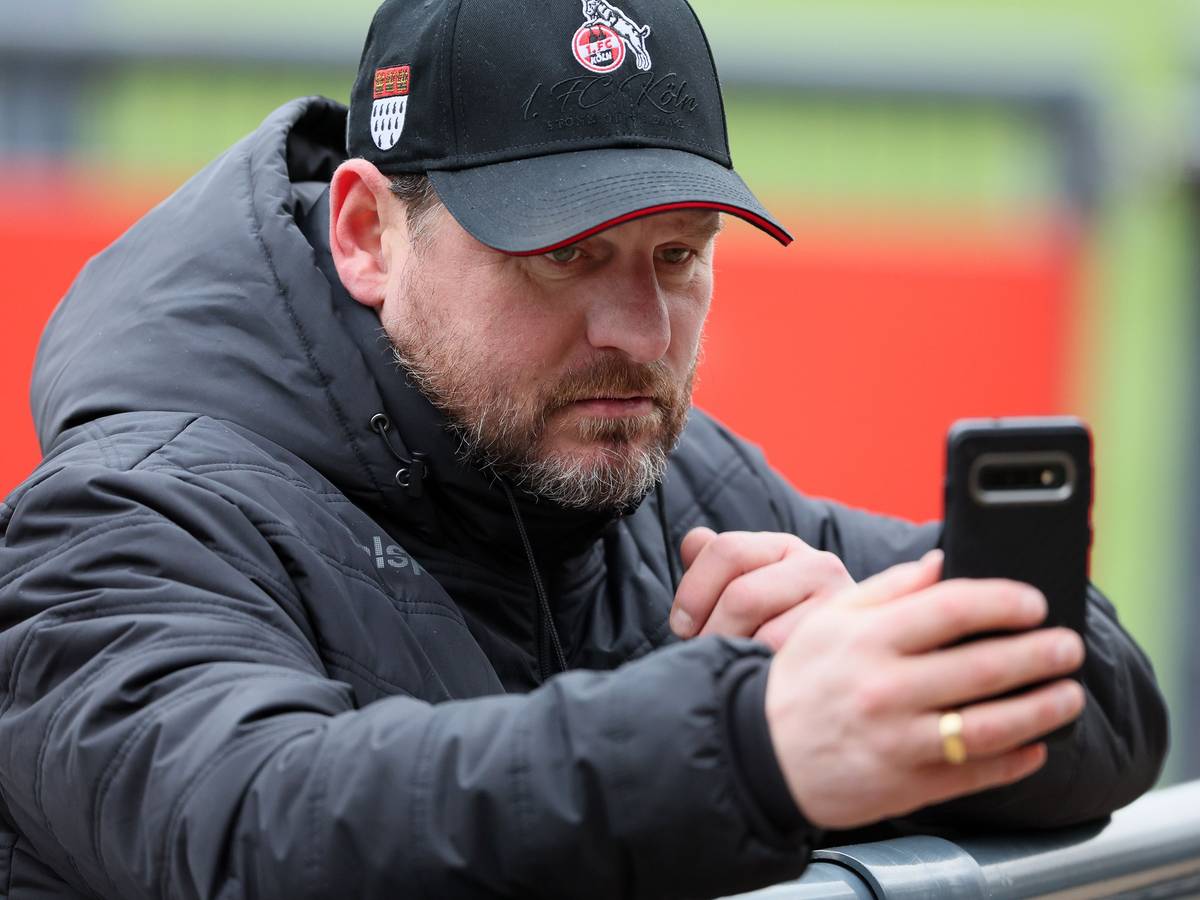 Steffen Baumgart schaut auf sein Smartphone