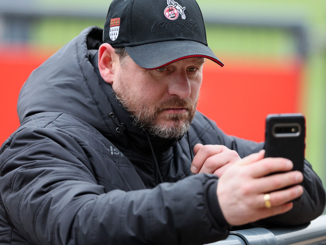 Steffen Baumgart schaut auf sein Smartphone
