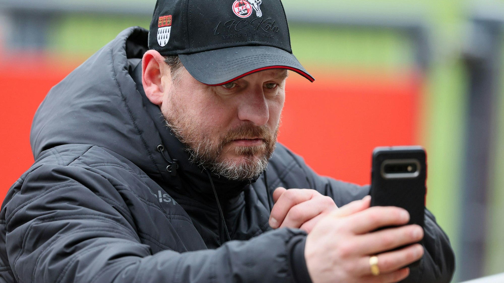 Steffen Baumgart schaut auf sein Smartphone