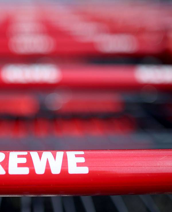Einkaufswagen stehen vor einem Rewe Supermarkt.