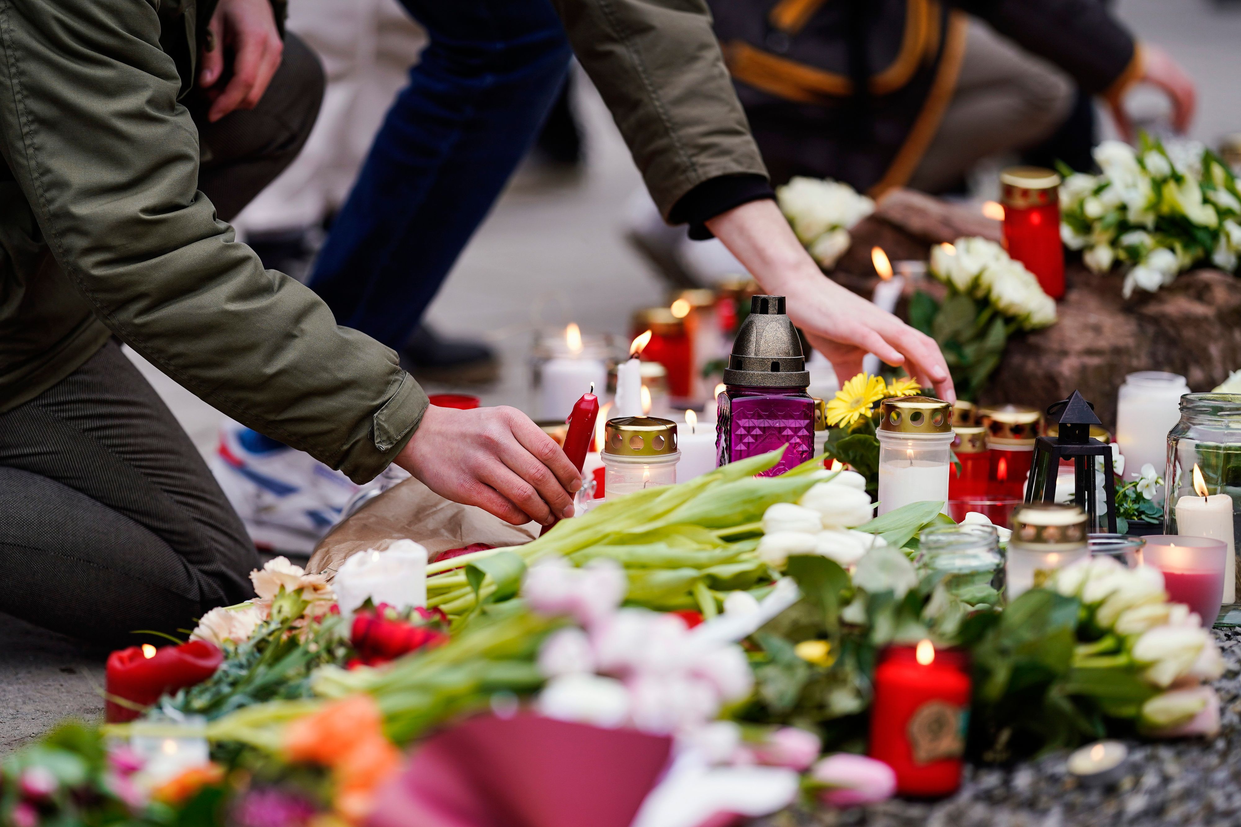 Nach Amoklauf auf Uni-Campus in Heidelberg legen Menschen am Dienstag, 25. Januar 2022, vor einem Gebäude der Universität Blumen und Kerzen an den Wegesrand.