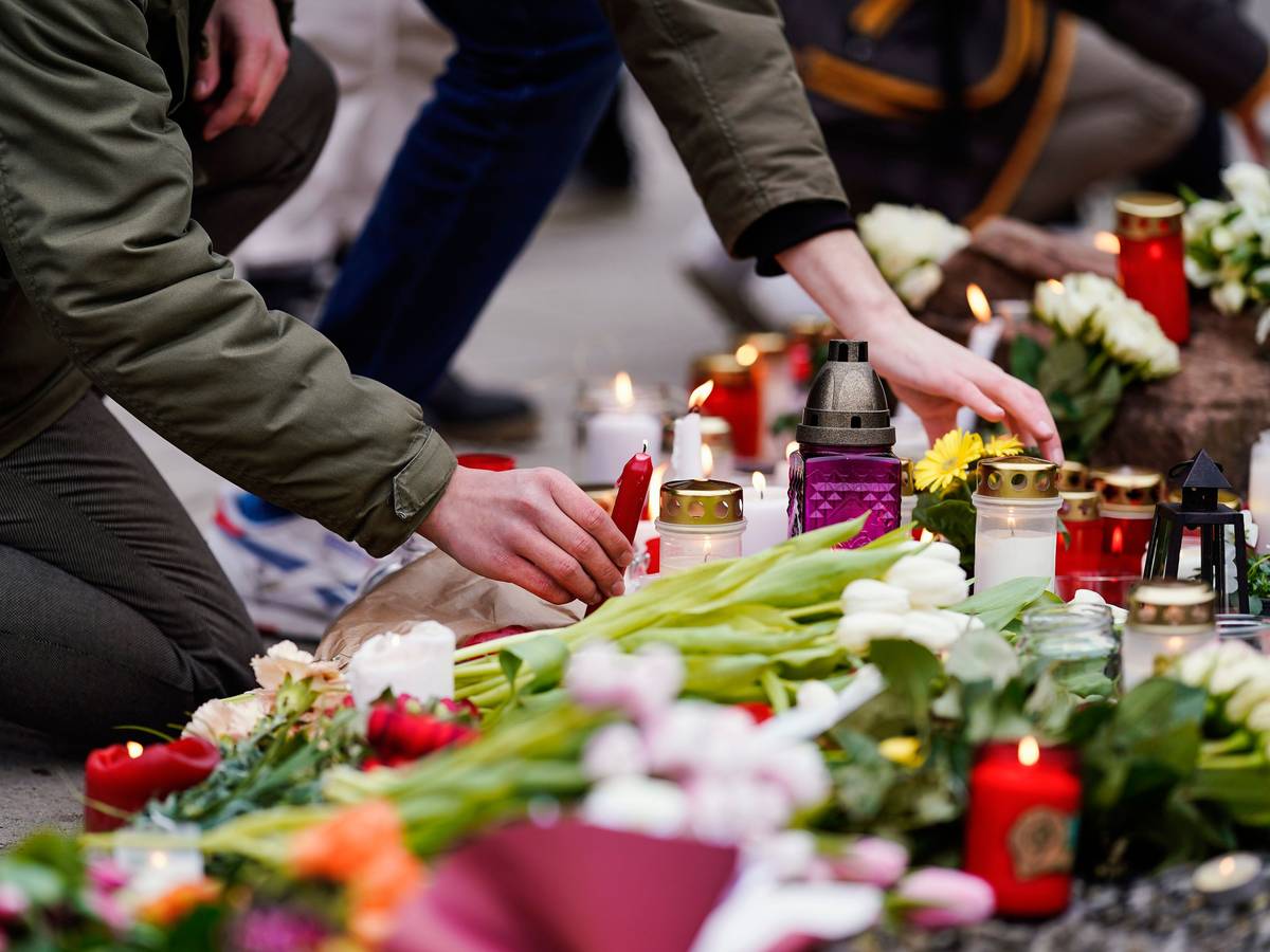 Nach Amoklauf auf Uni-Campus in Heidelberg legen Menschen am Dienstag, 25. Januar 2022, vor einem Gebäude der Universität Blumen und Kerzen an den Wegesrand.