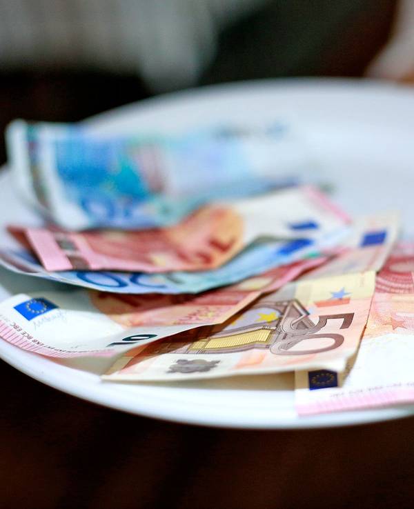 Undatiertes Foto von einer Kellnerin, die Geld auf dem Teller hat.