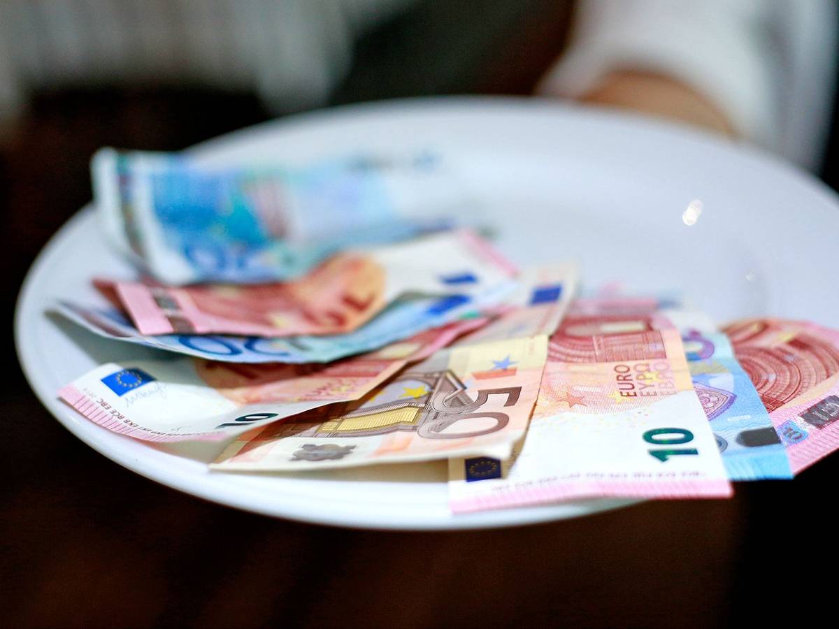 Undatiertes Foto von einer Kellnerin, die Geld auf dem Teller hat.
