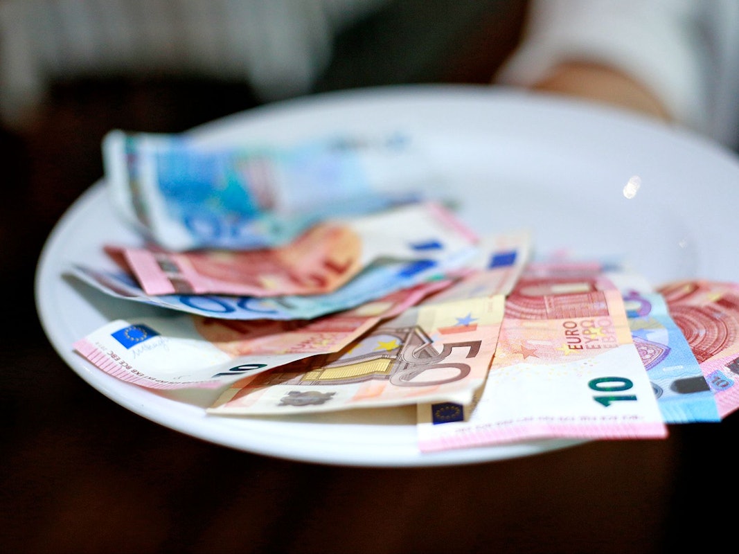 Undatiertes Foto von einer Kellnerin, die Geld auf dem Teller hat.