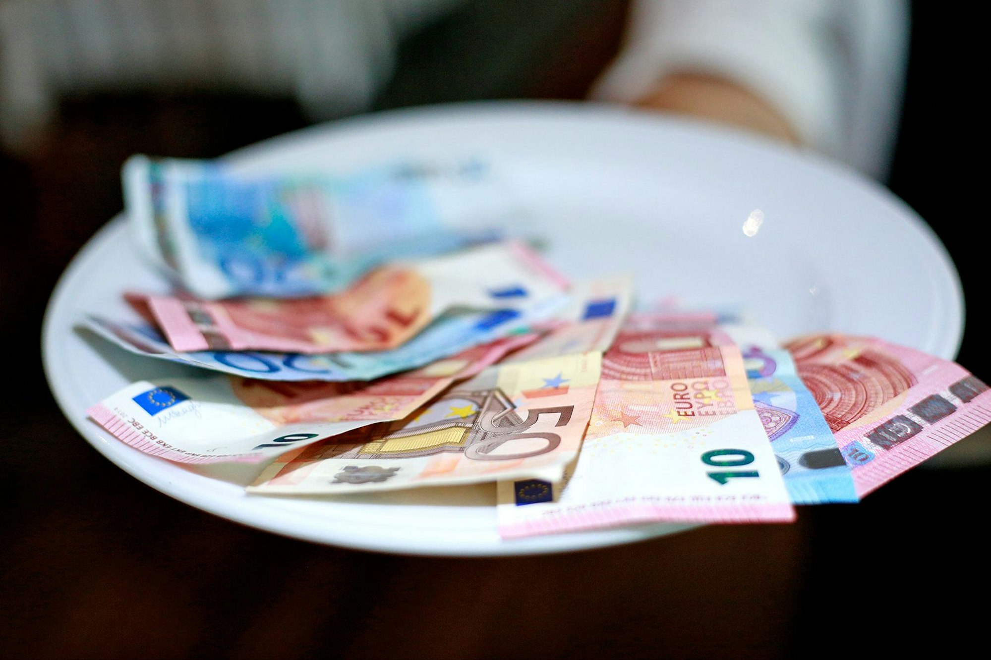 Undatiertes Foto von einer Kellnerin, die Geld auf dem Teller hat.