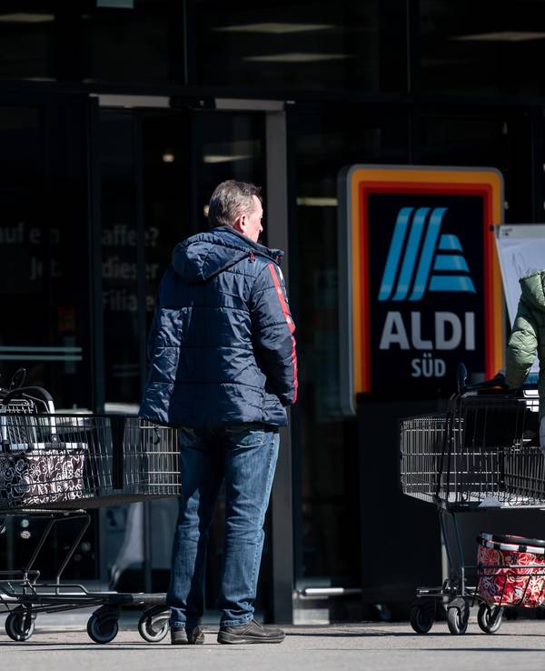 Menschen warten mit Abstand zueinander vor einer Filiale von Aldi Süd in Mülheim auf Einlass. Das Bild entstand am 23. März 2020.
