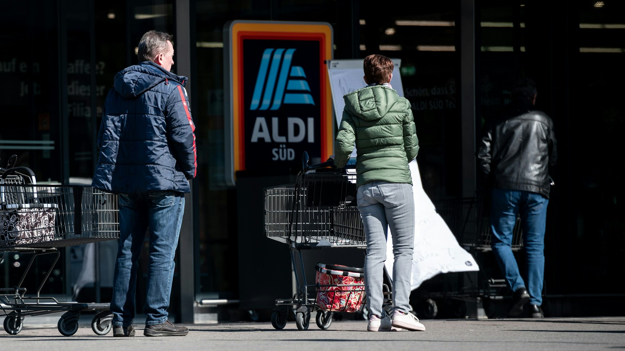 Menschen warten mit Abstand zueinander vor einer Filiale von Aldi Süd in Mülheim auf Einlass. Das Bild entstand am 23. März 2020.