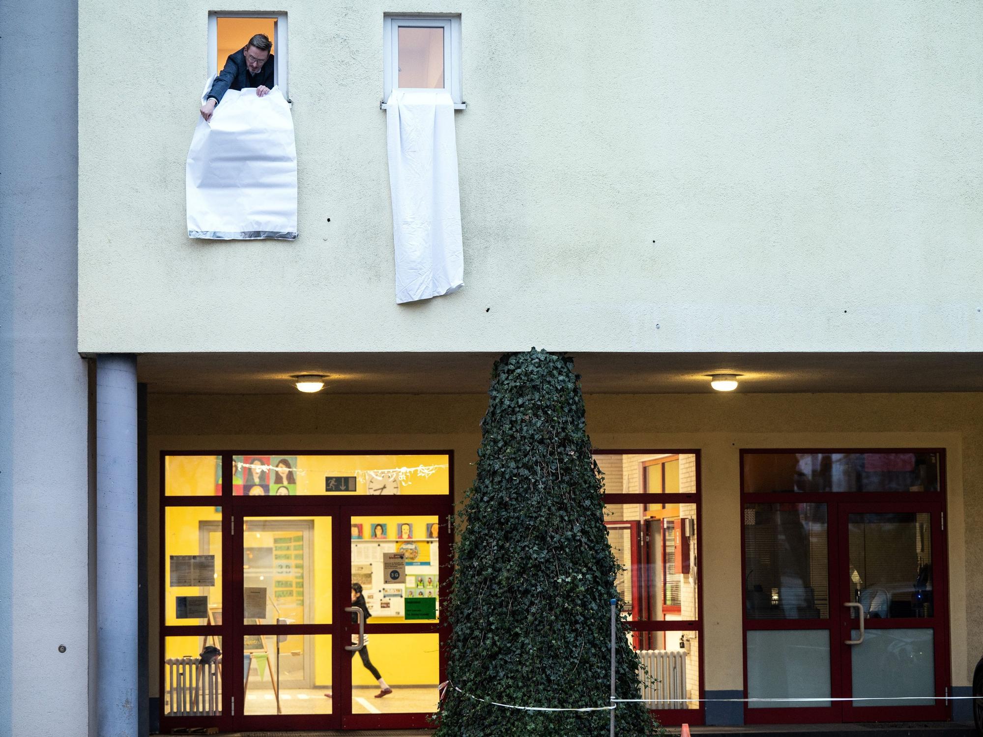 Ein Mann hängt eine weiße Fahne aus einem Fenster.
