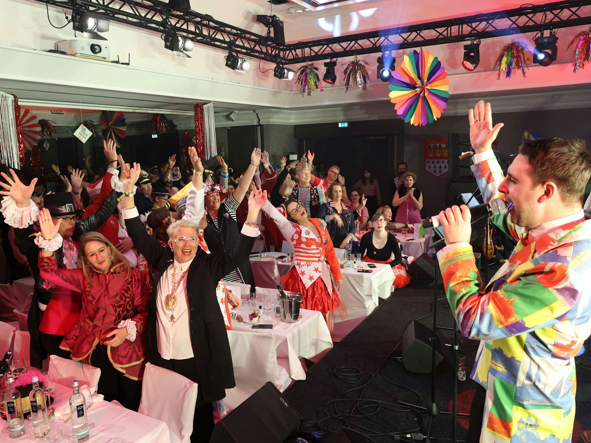 Tanzendes und mitsingendes kostümiertes Publikum in einem Saal.