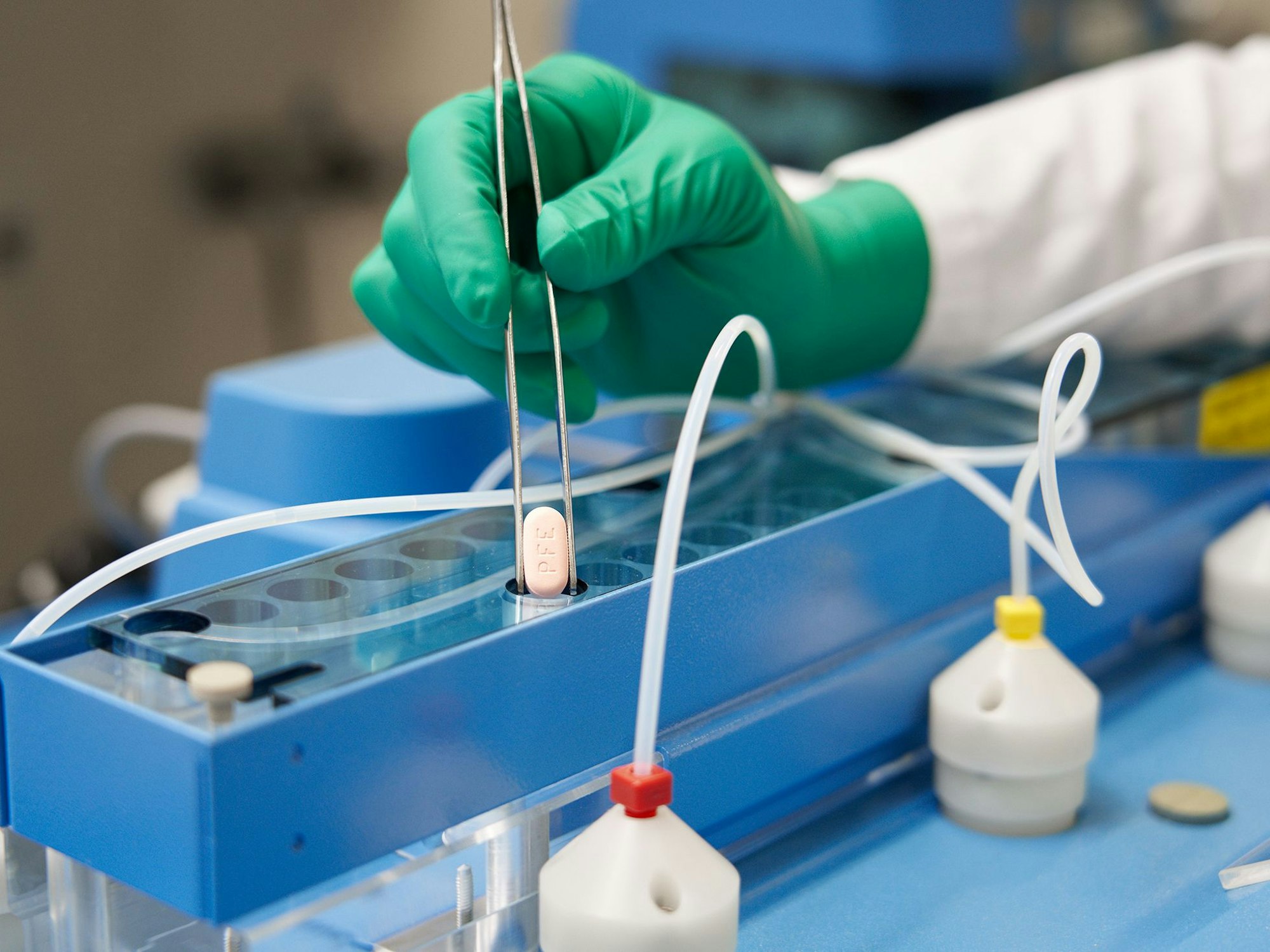 Ein Mitarbeiter von Pfizer hält eine Paxlovid-Tablette mit einer Zange.