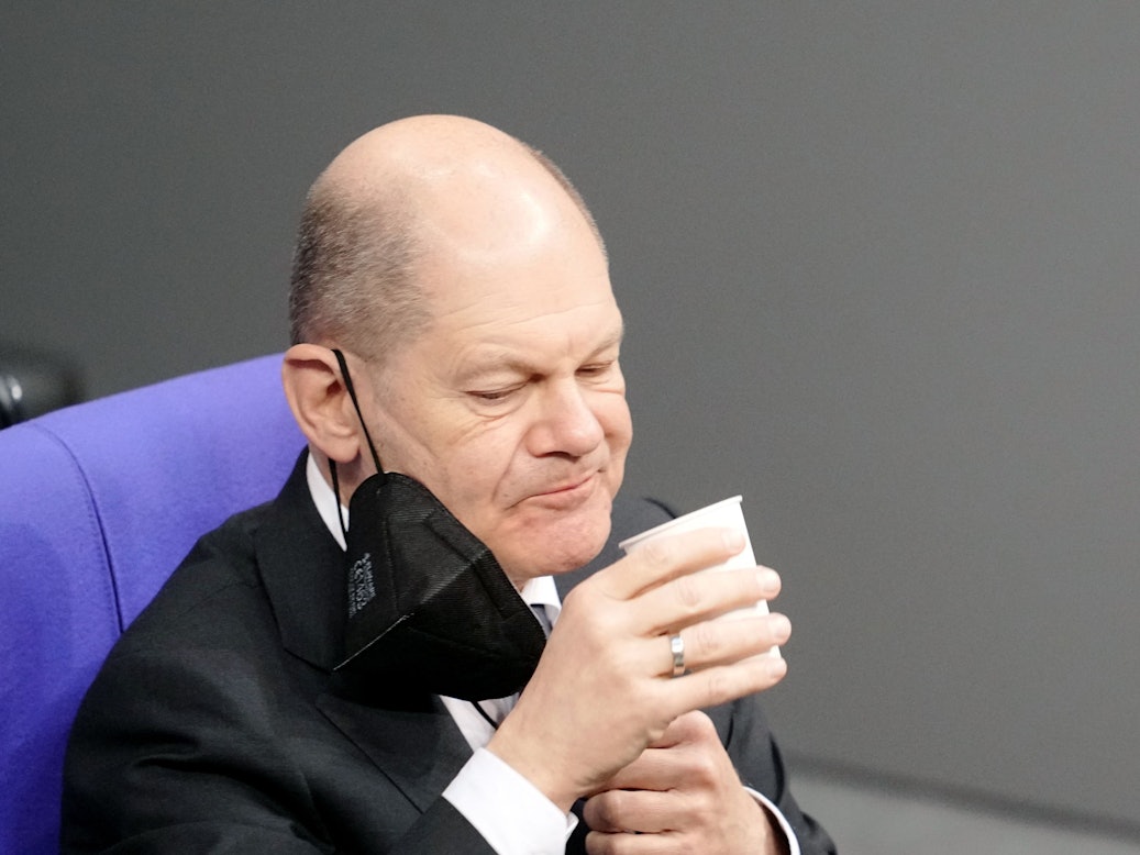 Bundeskanzler Olaf Scholz (SPD) nimmt an der Orientierungsdebatte zu einer SARS-CoV-2-Impfpflicht im Bundestag teil und trinkt etwas. Das Bild entstand am 26. Januar 2022.
