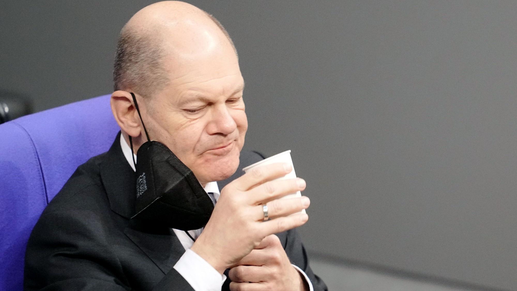 Bundeskanzler Olaf Scholz (SPD) nimmt an der Orientierungsdebatte zu einer SARS-CoV-2-Impfpflicht im Bundestag teil und trinkt etwas. Das Bild entstand am 26. Januar 2022.