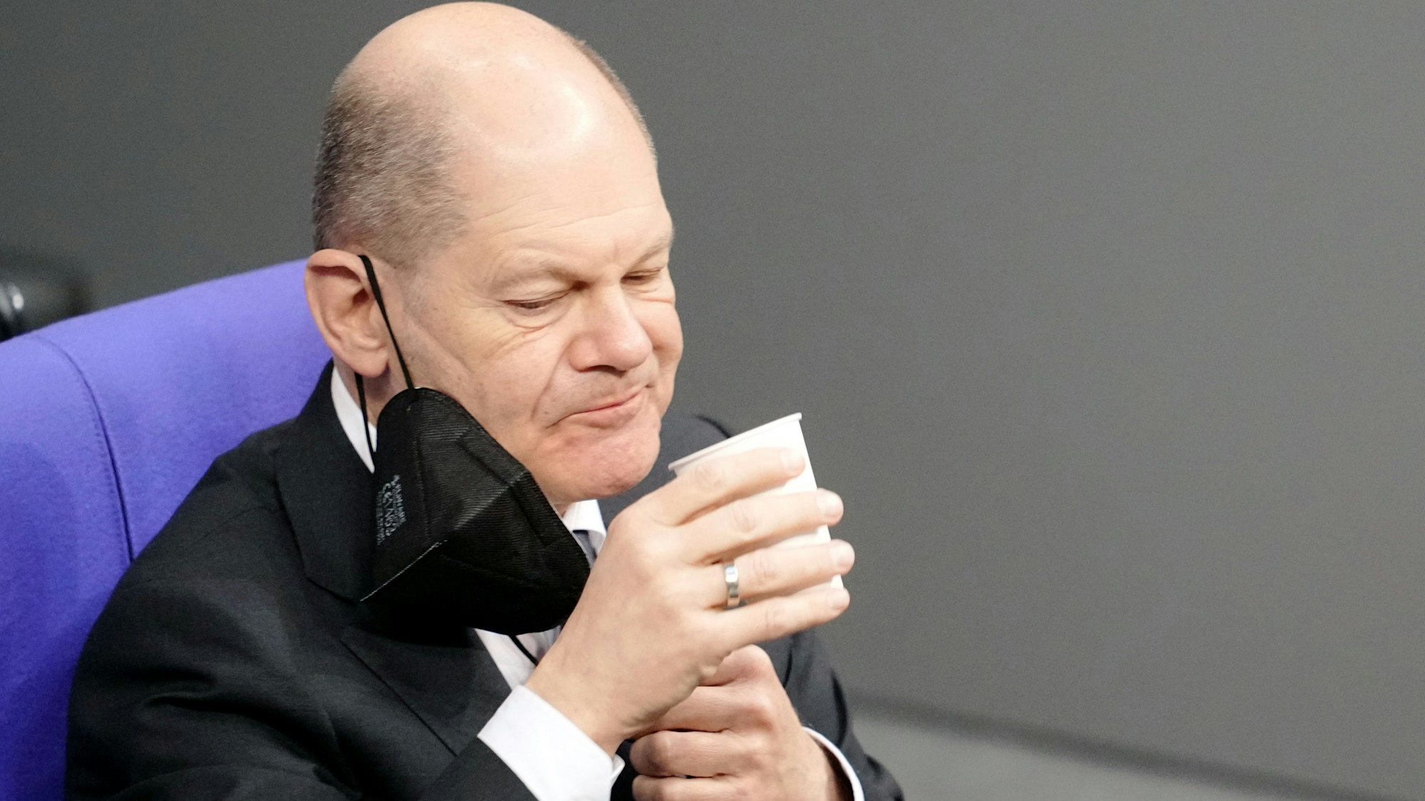 Bundeskanzler Olaf Scholz (SPD) nimmt an der Orientierungsdebatte zu einer SARS-CoV-2-Impfpflicht im Bundestag teil und trinkt etwas. Das Bild entstand am 26. Januar 2022.