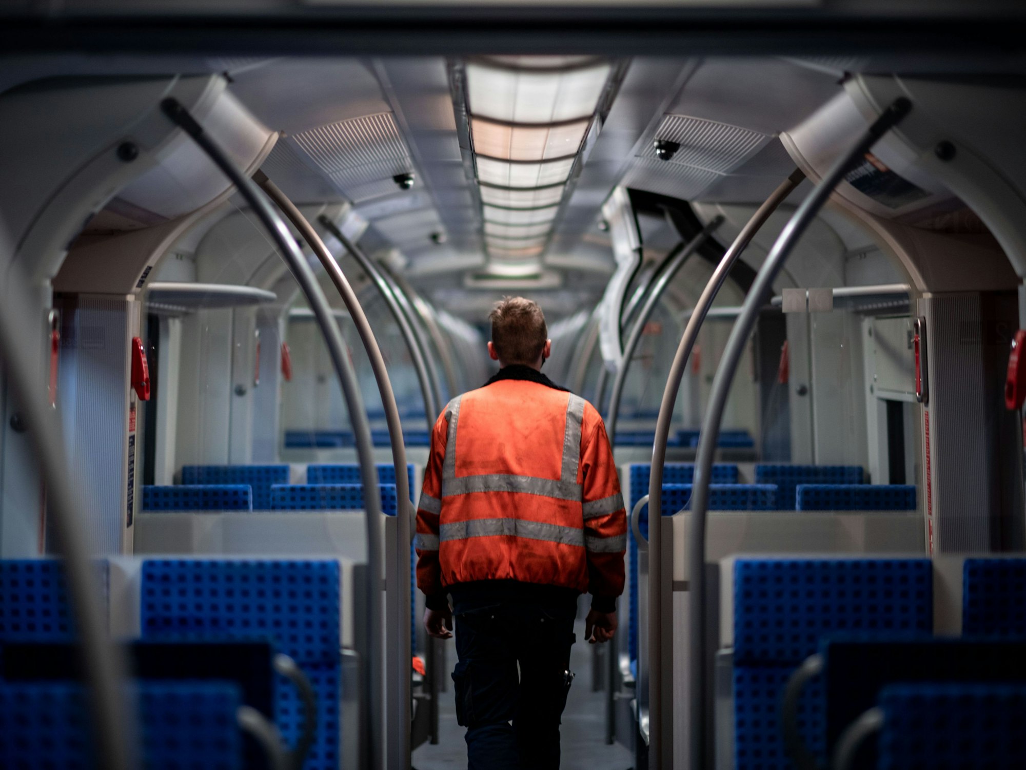 Ein Mitarbeiter der DB geht durch den Innenbereich eines Zuges.