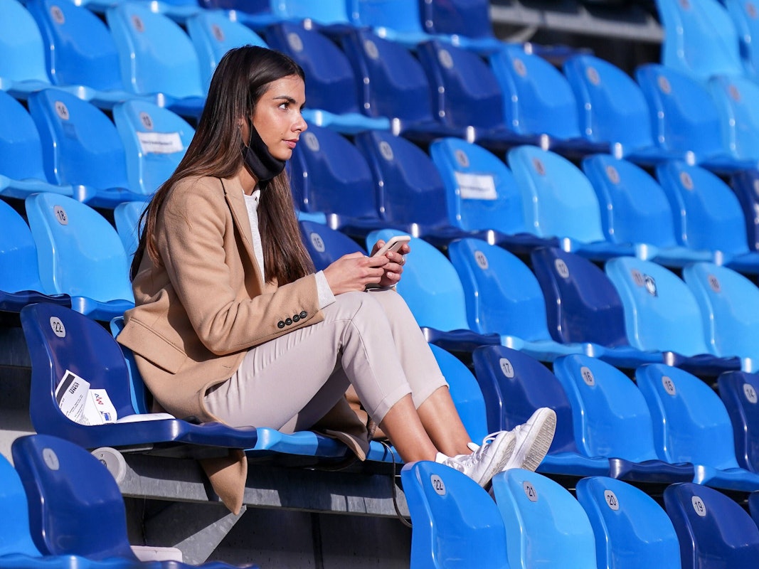 Lea Wagner sitzt auf der Tribüne und hat ihr Handy in der Hand.