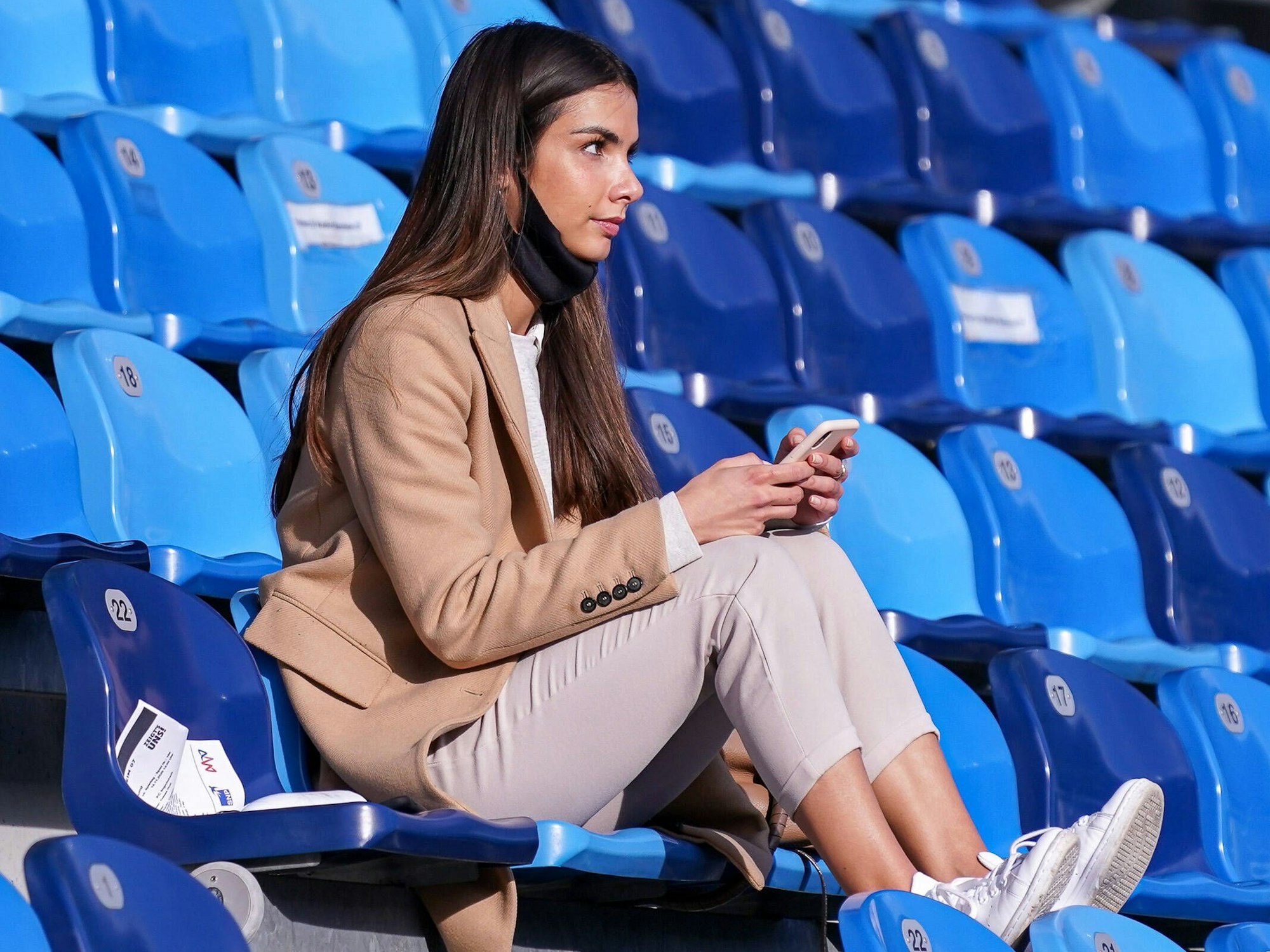 Lea Wagner sitzt auf der Tribüne und hat ihr Handy in der Hand.