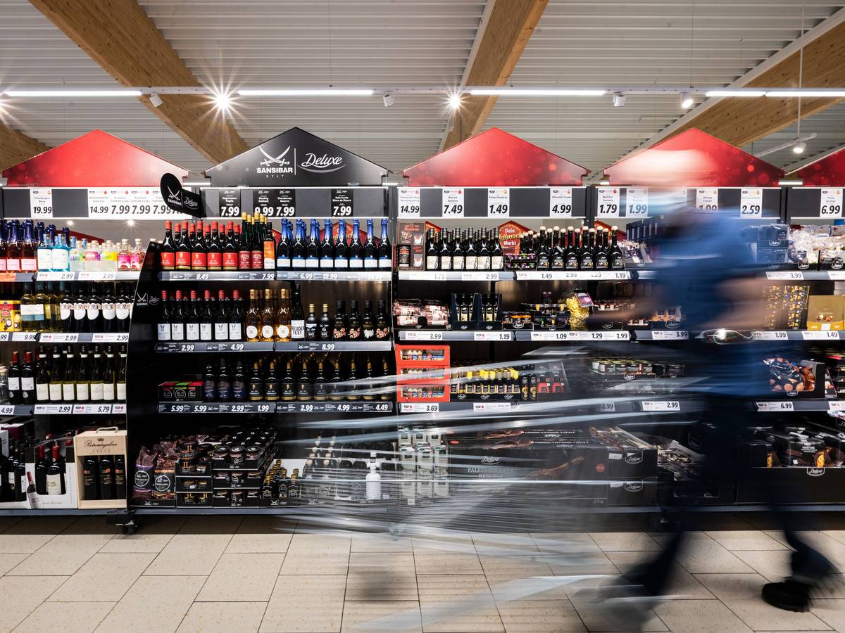 Ein Mann geht mit seinem Einkaufswagen in einer Lidl-Filiale an Regalen mit alkoholischen Getränken vorbei.